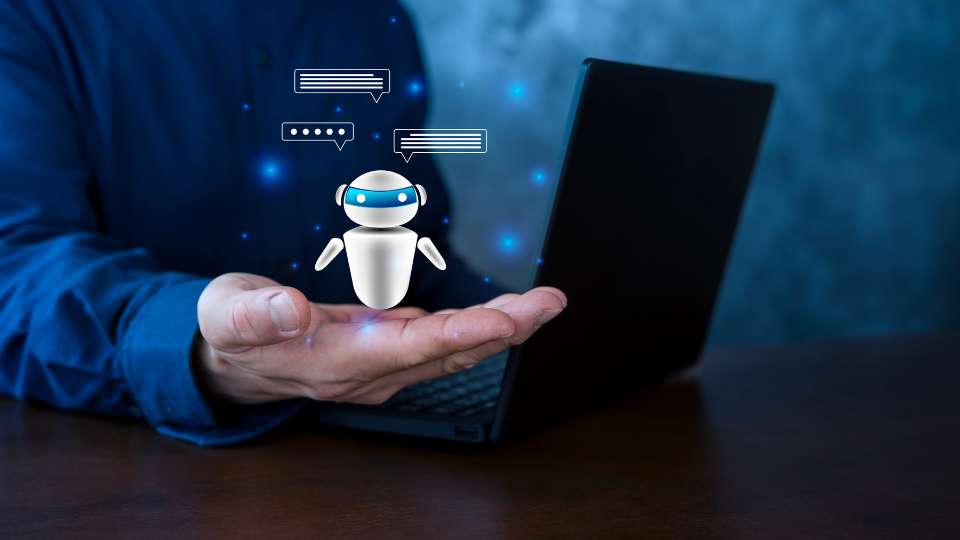 A digital composite image shows a person’s hand held open toward a laptop, with a small, glowing white robot icon floating above the palm. The robot is surrounded by speech bubble icons and blue light particles, symbolizing an AI assistant in mid-conversation. This visual represents the "Co-Author Network Check" strategy. It illustrates how researchers can use digital tools to probe for specific details, like a list of contributors, to ensure a reference isn't a "hallucination." By cross-referencing names on professional platforms, scholars can confirm the legitimacy of co-authorship in research and maintain the highest standards of academic integrity.