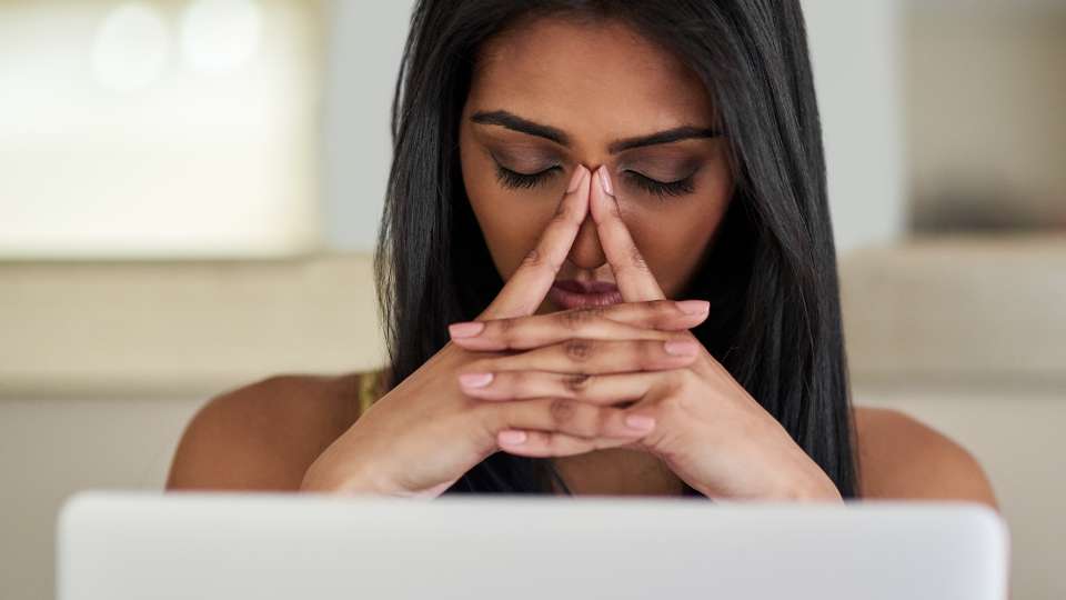 A close-up of a woman with closed eyes, pressing her fingers to the bridge of her nose in deep concentration or stress. This image illustrates the intense pressure and focus required to meticulously customize a research grant proposal.