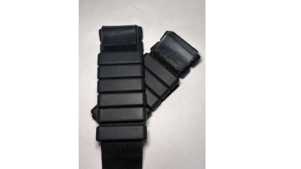 Two black, adjustable wearable weights with Velcro straps are shown against a white background. This discreet travel workout gear allows researchers to stay active on the go without disrupting their networking schedule at international conferences.